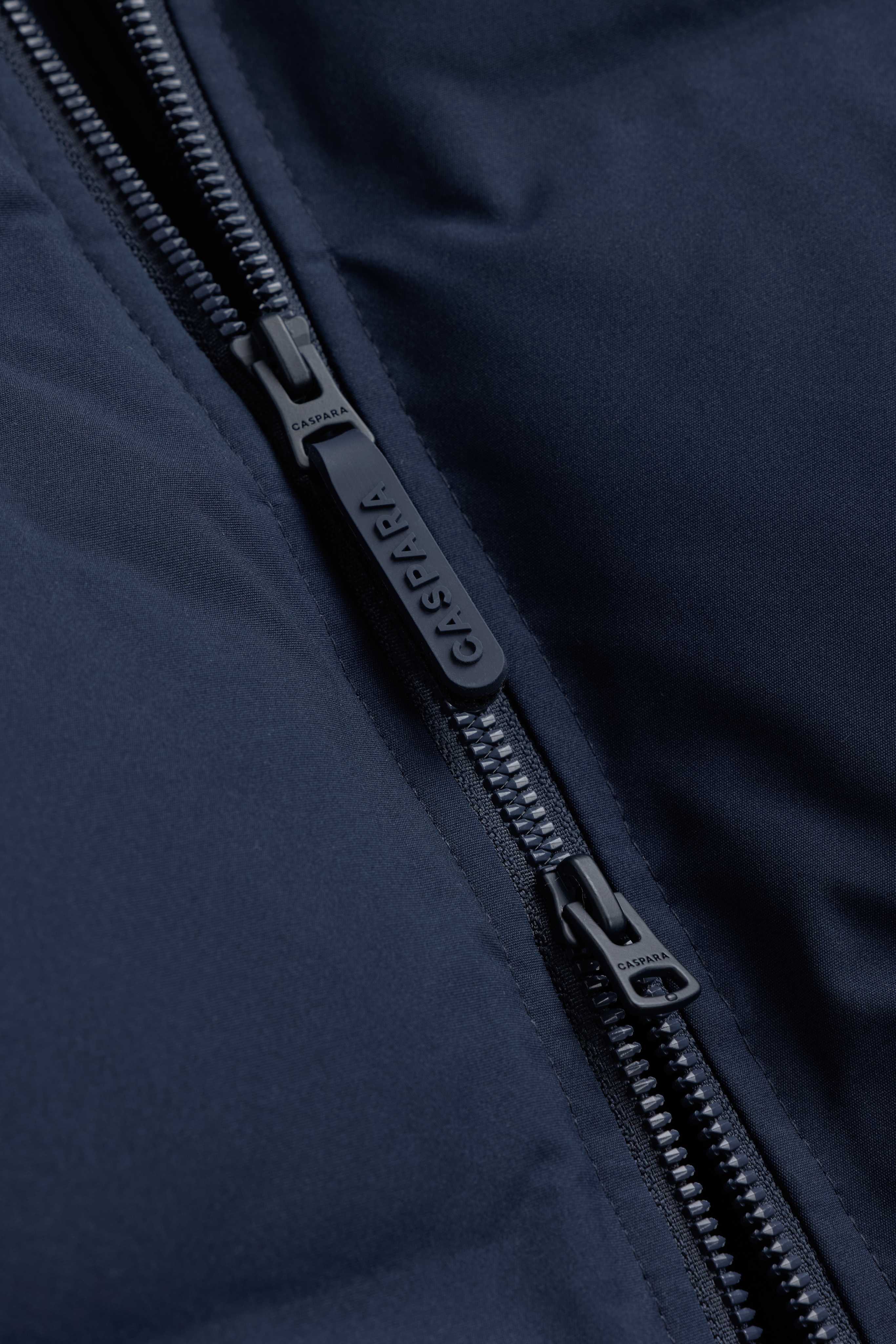 Close-up of the two-way front zipper with branded pullers on the navy CASPARA Boreal Puffer Jacket.
